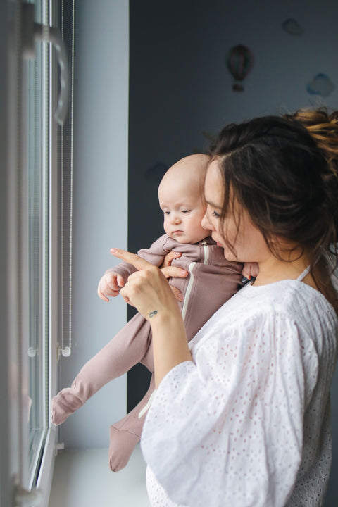 Mother holding her baby in soft window light, both calm and settled — the regulated state this guide helps parents practice